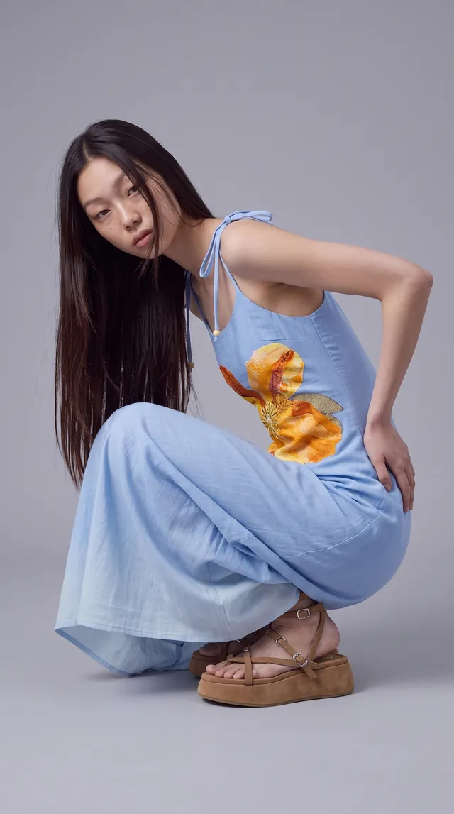 AI-generated still: the same model crouching in the flower dress